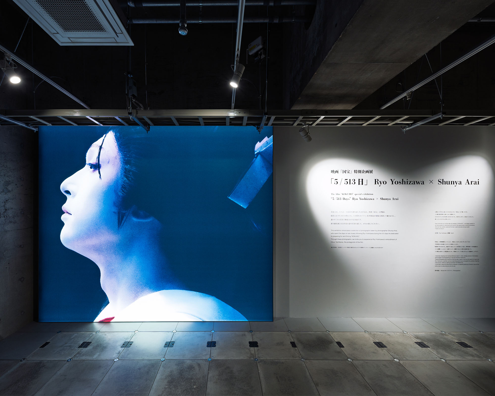 A display wall featuring large photographs alongside explanations about the exhibits. The lighting enhances the expressions of the photographs, while the background of the works and the intentions behind their creation are introduced through text.