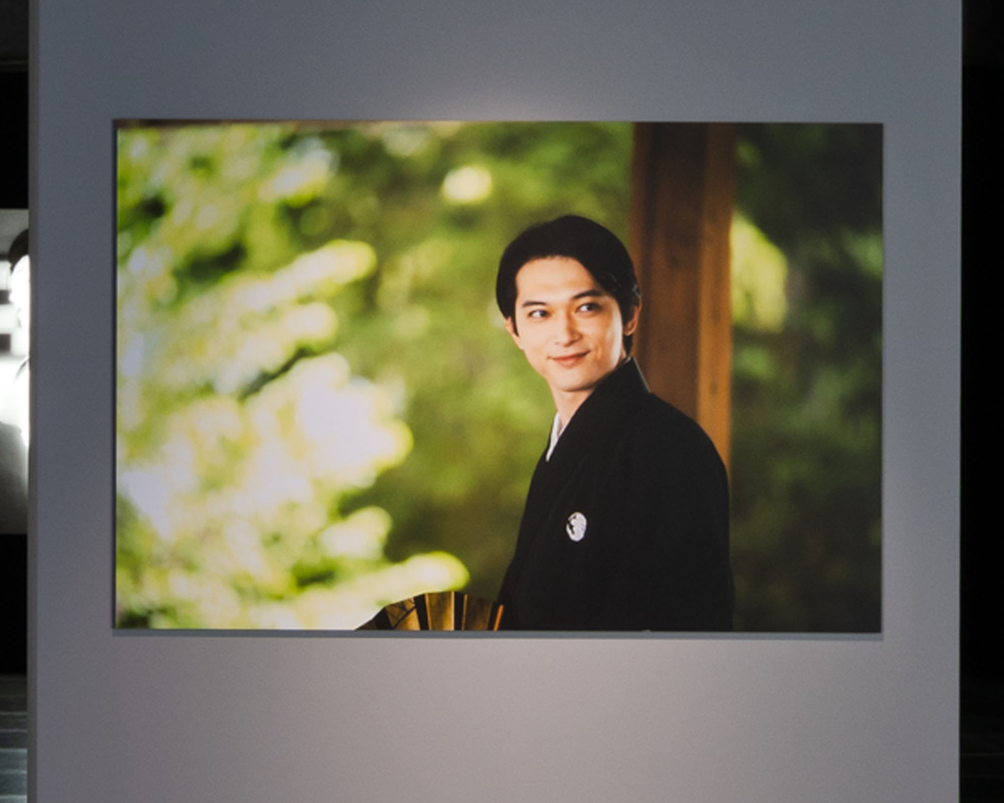 A photo of Ryo Yoshizawa during the filming of the Film "KOKUHO." The expression enveloped in soft light is striking and prominently displayed on the wall of the exhibition room.
