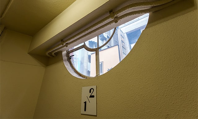 踊り場から見る丸窓。階数表示の文字もなんだかよい。