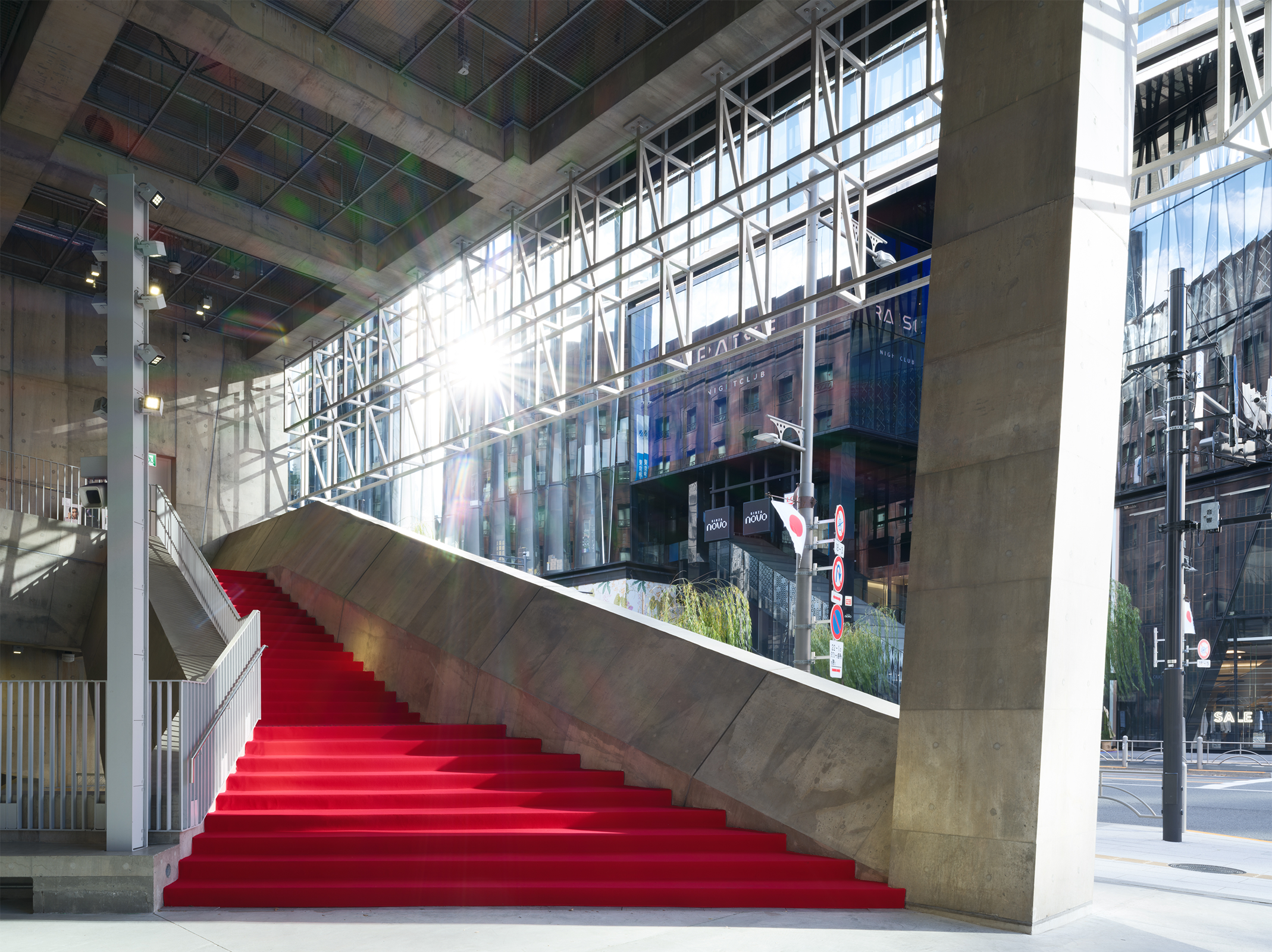 The red carpet laid on the stairs inside Ginza Sony Park stands out vividly against the concrete structure, with natural light streaming into the stairway space from outside.
